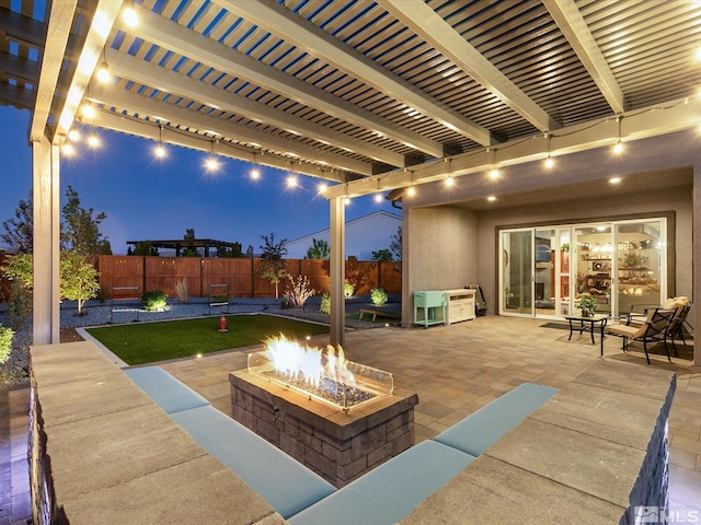 patio at night with a pergola and a fire pit