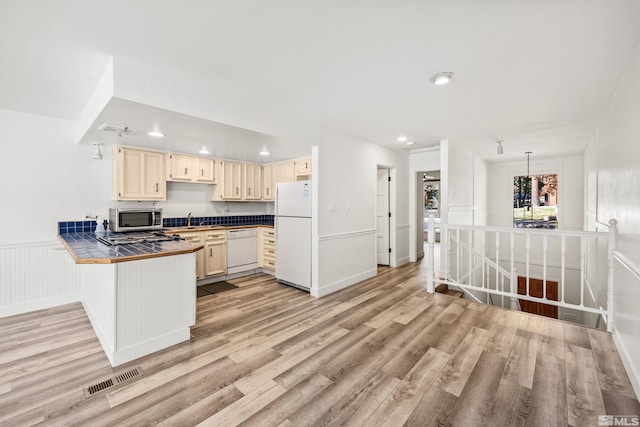 kitchen featuring white appliances, sink, decorative light fixtures, tile countertops, and light hardwood / wood-style flooring