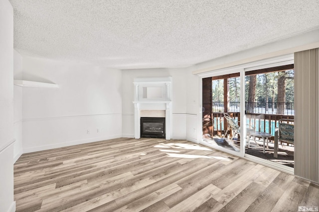 unfurnished living room with a textured ceiling and light hardwood / wood-style flooring