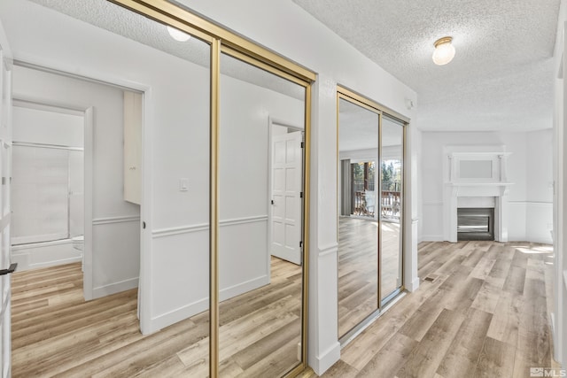 hall with a textured ceiling and light wood-type flooring