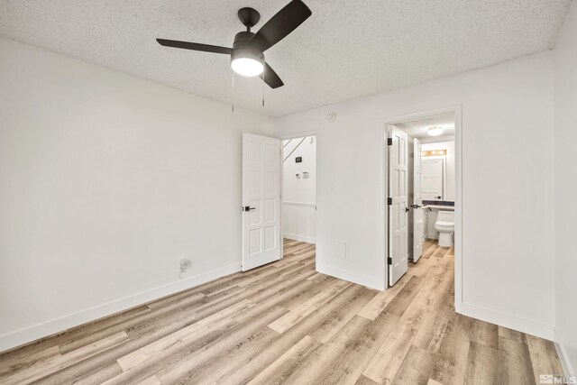 unfurnished bedroom with a textured ceiling, light hardwood / wood-style floors, ensuite bath, and ceiling fan