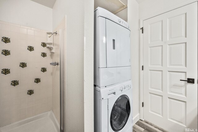 laundry room with hardwood / wood-style floors and stacked washer and clothes dryer