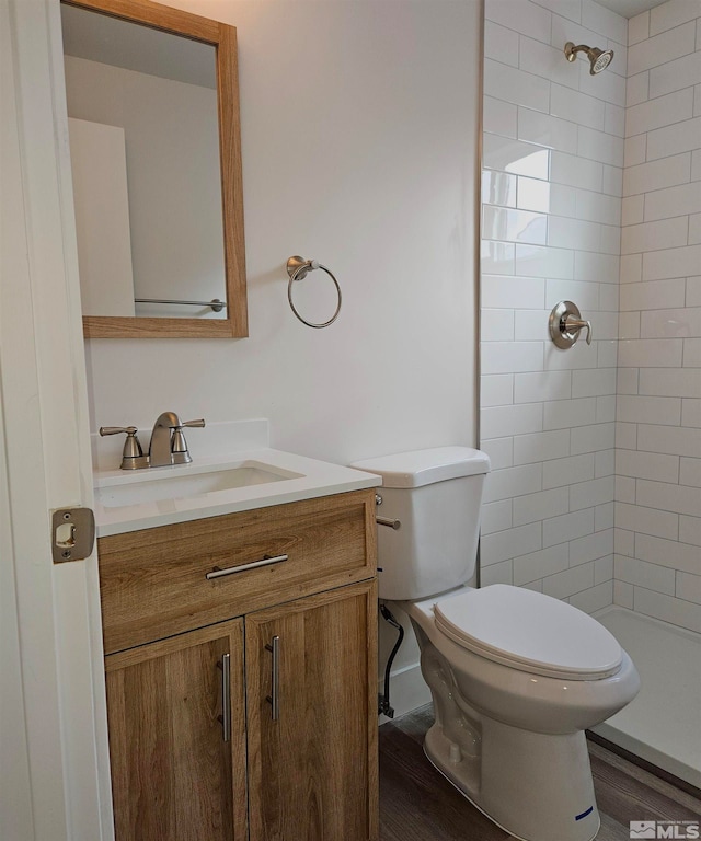 bathroom featuring vanity, toilet, wood-type flooring, and a tile shower