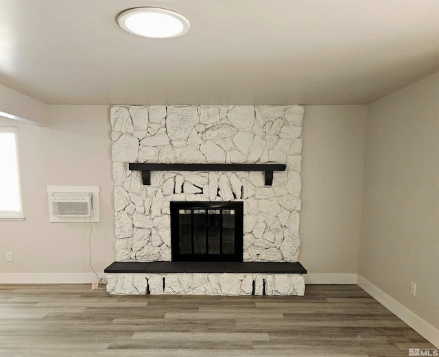 interior details with a stone fireplace, wood-type flooring, and an AC wall unit