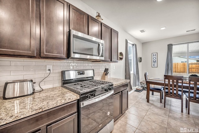 kitchen featuring tasteful backsplash, light stone counters, dark brown cabinets, and stainless steel appliances