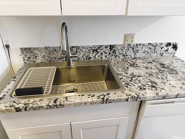 details featuring white dishwasher, white cabinetry, and sink