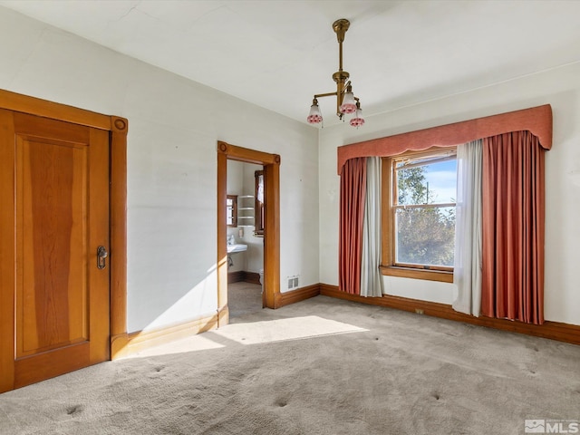 carpeted empty room featuring a notable chandelier