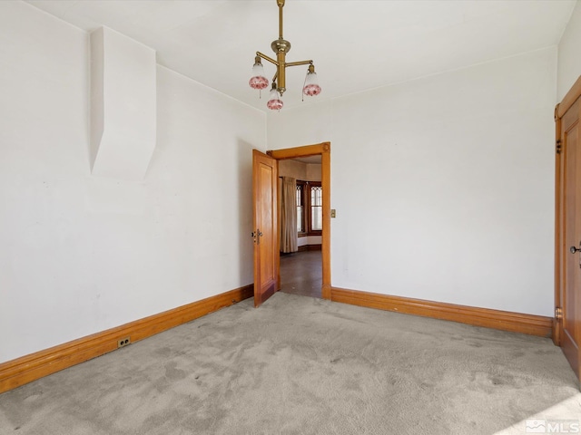 spare room featuring a notable chandelier and light carpet