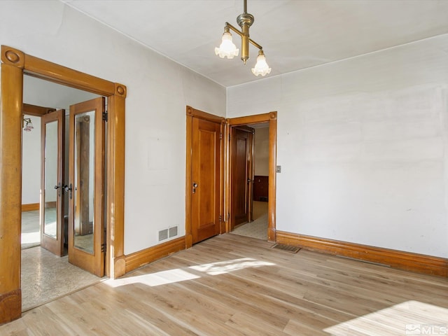 spare room with an inviting chandelier and hardwood / wood-style flooring