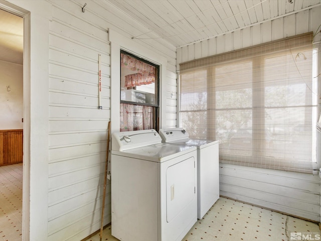 washroom featuring a wealth of natural light, wooden walls, and washing machine and dryer