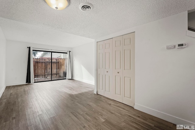 empty room with wood-type flooring and a textured ceiling