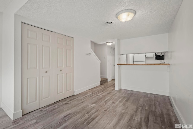 unfurnished living room featuring a textured ceiling and light wood-type flooring