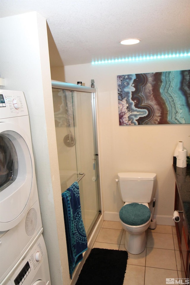 bathroom with tile patterned flooring, a shower with door, and stacked washer / dryer