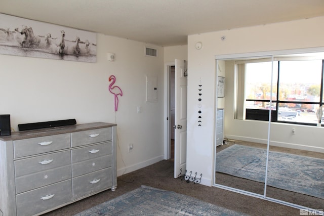 unfurnished bedroom featuring electric panel, a closet, and dark colored carpet