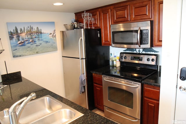 kitchen with stainless steel appliances, dark stone counters, and sink