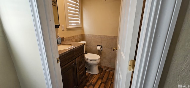 bathroom featuring hardwood / wood-style floors, vanity, tile walls, and toilet