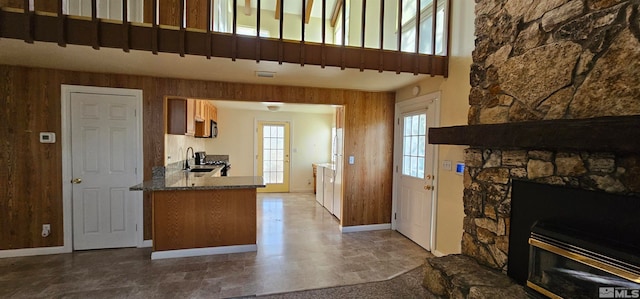 kitchen featuring plenty of natural light, wood walls, a stone fireplace, and sink