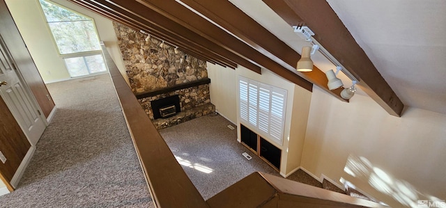 unfurnished living room with a stone fireplace, carpet floors, and lofted ceiling with beams