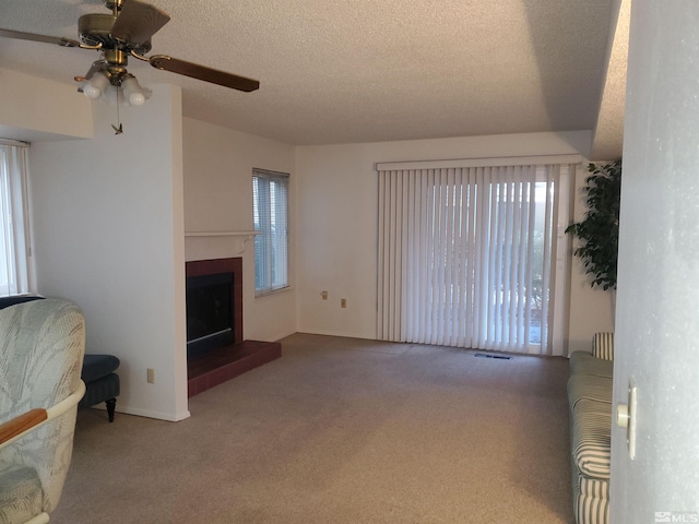 carpeted living room featuring ceiling fan, a healthy amount of sunlight, and a textured ceiling