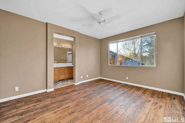 unfurnished bedroom featuring hardwood / wood-style floors, ensuite bath, and ceiling fan