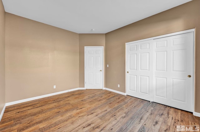 unfurnished bedroom with wood-type flooring and a closet