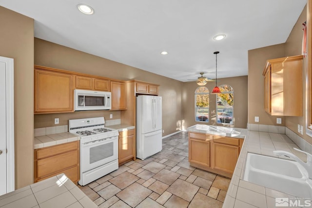 kitchen featuring tile counters, decorative light fixtures, white appliances, and sink