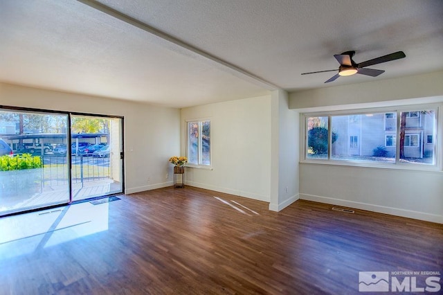 spare room with ceiling fan, plenty of natural light, dark wood-type flooring, and a textured ceiling