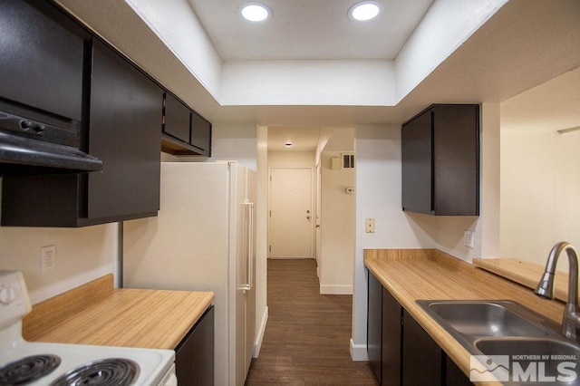 kitchen featuring sink, dark hardwood / wood-style floors, stove, white fridge, and extractor fan