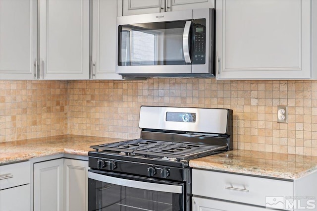 kitchen featuring white cabinets, decorative backsplash, light stone counters, and stainless steel appliances