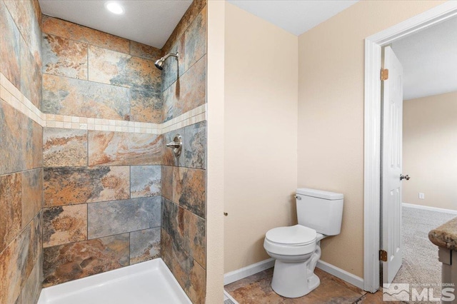 bathroom with tiled shower, tile patterned floors, and toilet