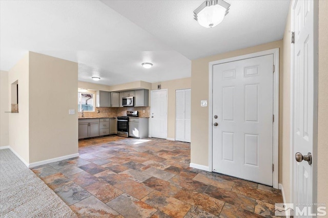 kitchen with decorative backsplash, appliances with stainless steel finishes, gray cabinetry, and sink