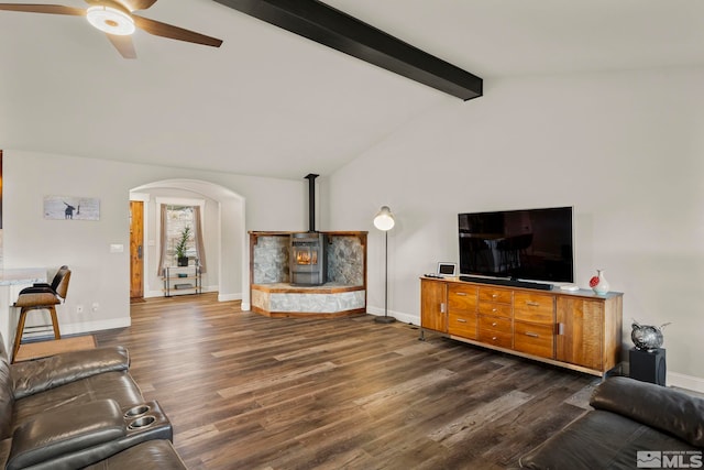 living room featuring beam ceiling, a wood stove, ceiling fan, and dark hardwood / wood-style floors