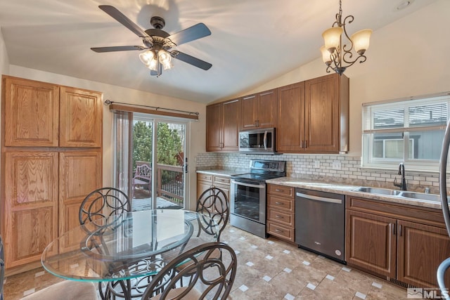 kitchen with sink, hanging light fixtures, stainless steel appliances, lofted ceiling, and decorative backsplash