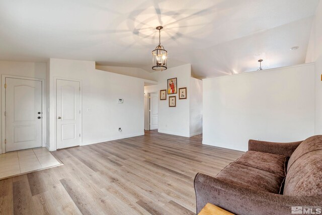 unfurnished living room featuring vaulted ceiling, light wood-type flooring, and a chandelier