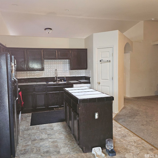 kitchen with light carpet, black refrigerator, sink, tasteful backsplash, and dark brown cabinetry