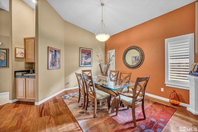 dining space with light hardwood / wood-style floors and vaulted ceiling