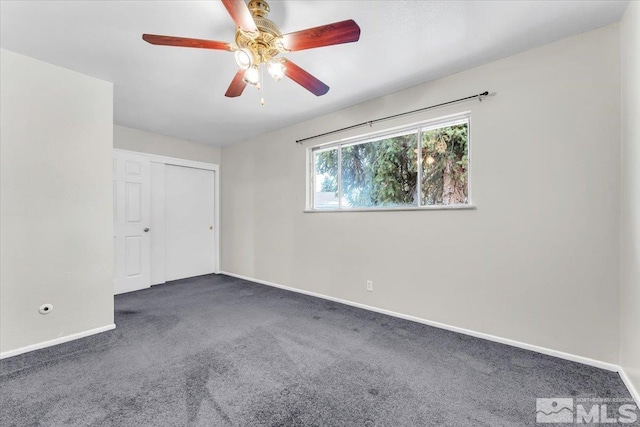 spare room featuring dark carpet and ceiling fan