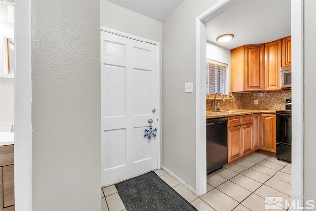 kitchen with decorative backsplash, light stone counters, sink, black appliances, and light tile patterned floors