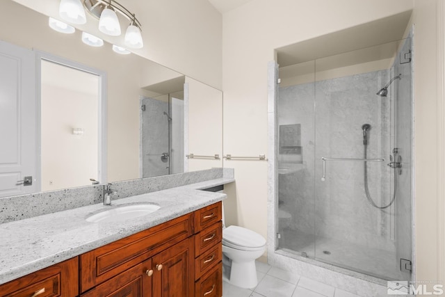 bathroom with tile patterned floors, vanity, a shower with shower door, and toilet