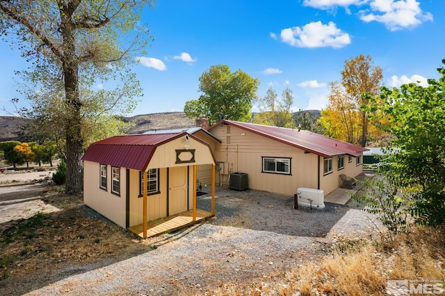 view of front of home featuring central air condition unit and a shed