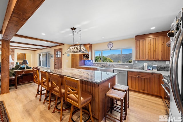 kitchen featuring beam ceiling, a kitchen bar, light hardwood / wood-style floors, and stainless steel appliances