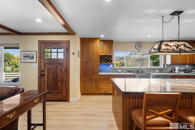 kitchen with decorative backsplash, light hardwood / wood-style floors, plenty of natural light, and hanging light fixtures