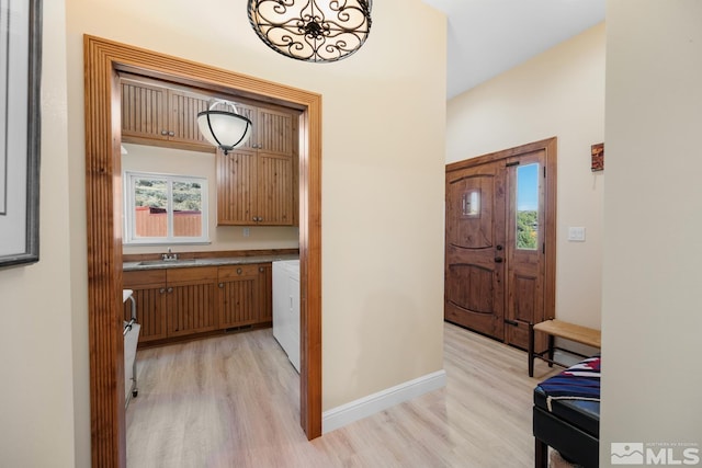 interior space with washing machine and dryer, light hardwood / wood-style flooring, and sink