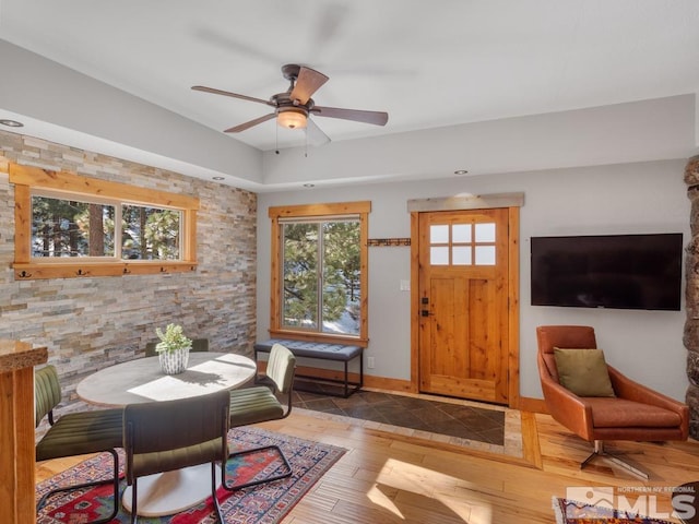 interior space featuring light wood-style flooring, baseboards, and a ceiling fan