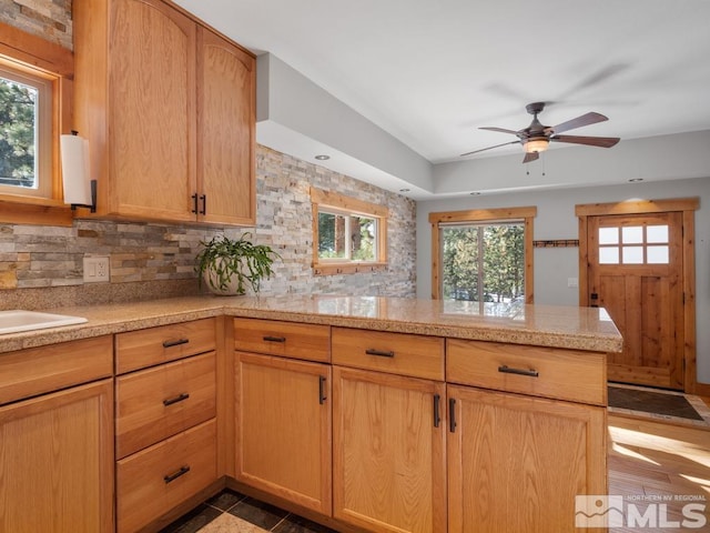 kitchen featuring a wealth of natural light, light countertops, a peninsula, and decorative backsplash