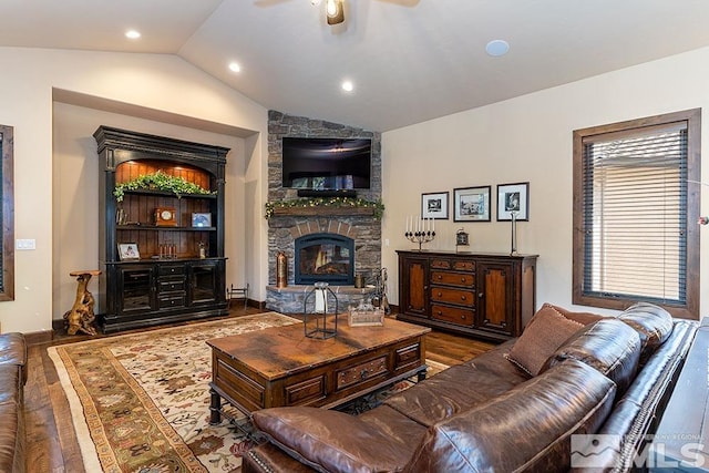 living room with dark hardwood / wood-style flooring, a stone fireplace, ceiling fan, and lofted ceiling