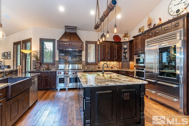 kitchen featuring hanging light fixtures, light wood-type flooring, a kitchen island with sink, and high quality appliances