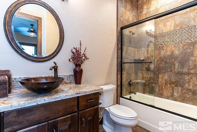 full bathroom featuring toilet, combined bath / shower with glass door, and vanity