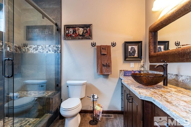 bathroom with wood-type flooring, vanity, toilet, and walk in shower