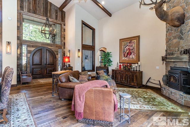 living room with dark hardwood / wood-style flooring, high vaulted ceiling, beamed ceiling, a chandelier, and a wood stove